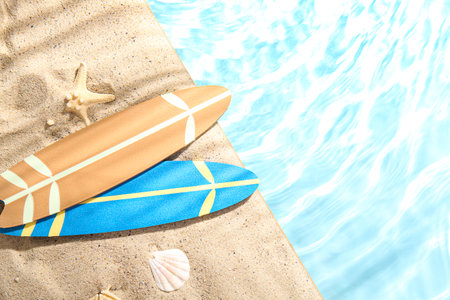 Mini surfboards with starfish and seashell on sand near waterの写真素材