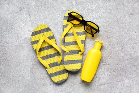 Sunglasses with flip flops and bottle of sunscreen cream on grunge gray backgroundの写真素材