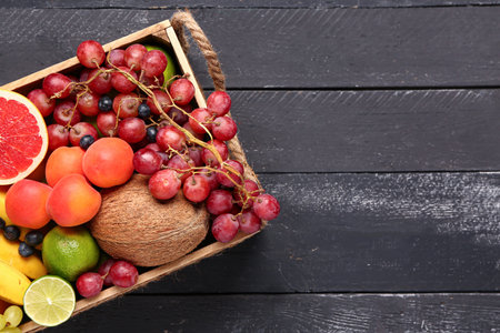 Box with different fresh fruits on black wooden backgroundの写真素材