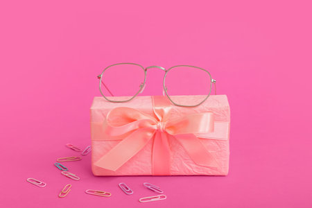 Gift box with eyeglasses and paper clips on pink backgroundの写真素材