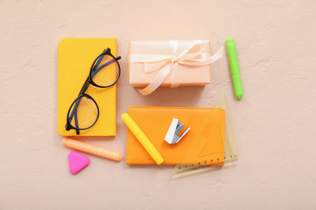 Gift box with eyeglasses and different stationery on orange background