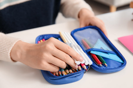 Female student with pencil case at table, closeup