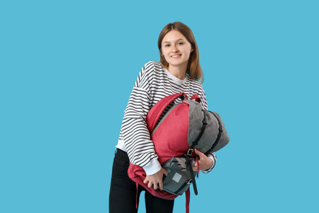 Female student with backpack on blue background