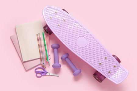 Skateboard with dumbbells and different stationery on pink backgroundの写真素材