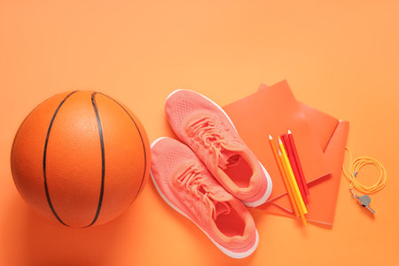Sneakers with ball, whistle and different stationery on orange backgroundの写真素材