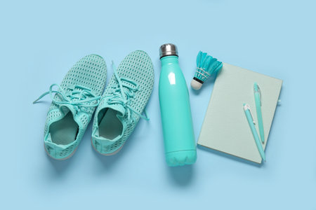 Sneakers with bottle of water, badminton shuttlecock and stationery on blue backgroundの写真素材