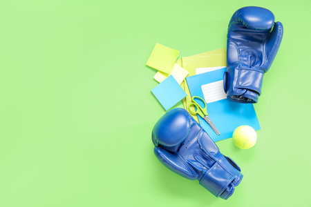 Boxing gloves with tennis ball and different stationery on green backgroundの写真素材