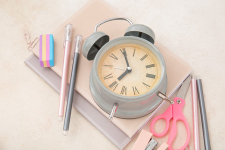 Alarm clock with different stationery on gray background