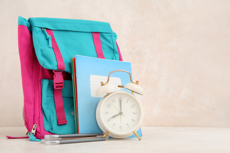 Backpack with alarm clock and different stationery on white tableの写真素材