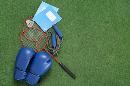 Notebooks with boxing gloves, badminton rackets and skipping rope on color backgroundの写真素材