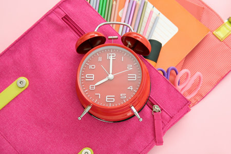 Backpack with alarm clock and different stationery on pink backgroundの写真素材