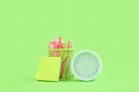 Alarm clock with different stationery on green background