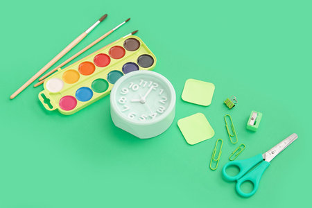 Alarm clock with different stationery on green background