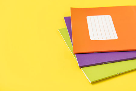 Different colorful notebooks on yellow backgroundの写真素材