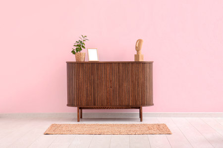Modern chest of drawers with houseplant and blank picture near pink wall in roomの写真素材