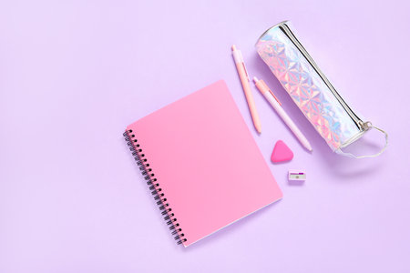 Notebook with pencil case and different stationery on lilac backgroundの写真素材