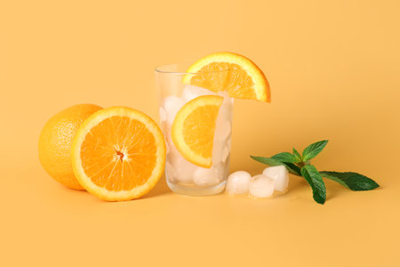 Glass of ice cubes with oranges and mint on color backgroundの写真素材