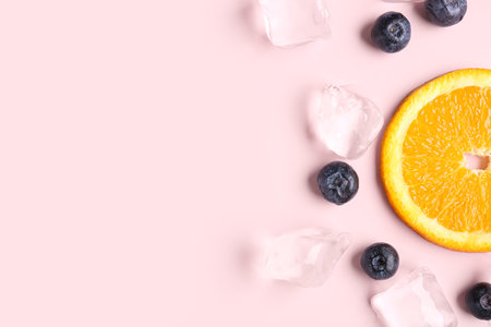 Orange slice with ice cubes and blueberries on pink backgroundの写真素材
