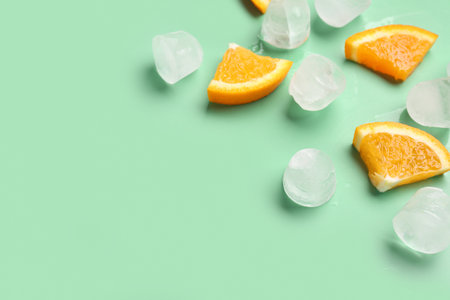 Orange pieces with ice cubes on turquoise backgroundの写真素材