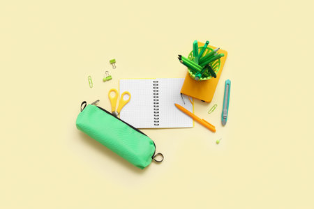 Notebook and school stationery on yellow background