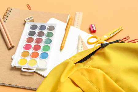 School backpack with paints and stationery on orange background, closeupの写真素材