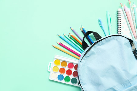 School backpack with different colorful pencils and paints on turquoise backgroundの写真素材
