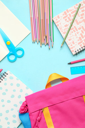 Frame made of school backpack and different stationery on blue backgroundの写真素材