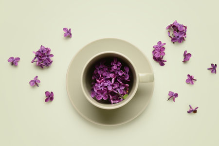 Cup with beautiful lilac flowers on beige backgroundの写真素材