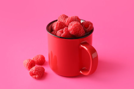 Cup with fresh raspberries on pink backgroundの写真素材