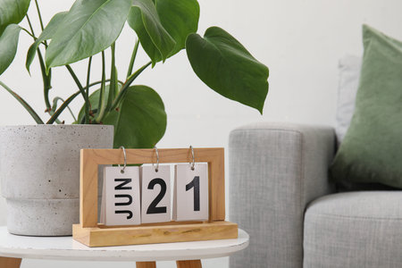 Stylish gray sofa, table with houseplant and calendar near light wall in living room, closeup