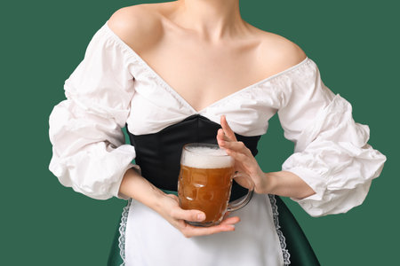Beautiful Octoberfest waitress with beer on green background, closeupの写真素材