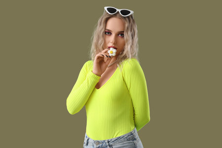 Young woman with candy in shape of flower on green background
