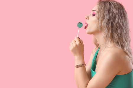 Young woman with lollipop on pink backgroundの写真素材