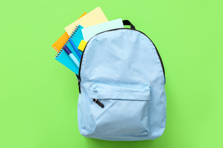 Blue school backpack with notebooks and markers on green backgroundの写真素材