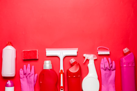 Different cleaning supplies on red backgroundの写真素材