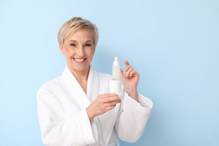 Mature woman with cosmetic products on blue backgroundの写真素材