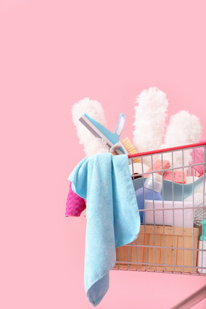 Shopping cart full of cleaning supplies on pink backgroundの写真素材