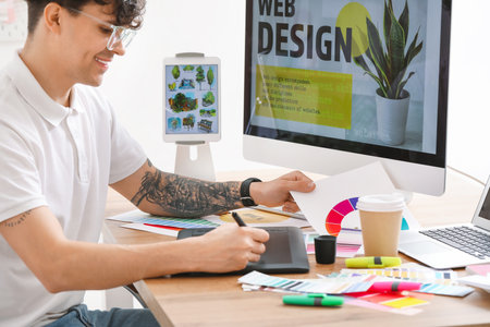 Male graphic designer working with tablet and color palette in officeの写真素材