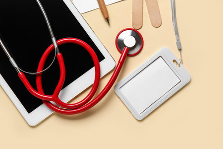 Stethoscope, tablet computer and badge on yellow backgroundの写真素材
