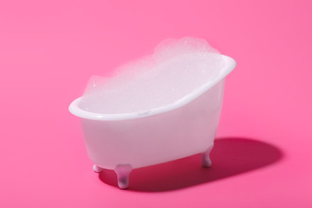 Small bathtub with foam on pink backgroundの写真素材