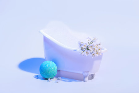 Small bathtub with foam, flowers and bath bomb on color backgroundの写真素材