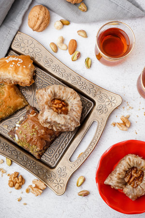 Tray with tasty baklava and glass of Turkish tea on light backgroundの写真素材