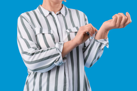 Mature woman rolling up her sleeve on light blue backgroundの写真素材
