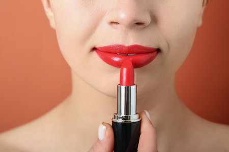 Woman applying red lipstick on color background, closeupの写真素材
