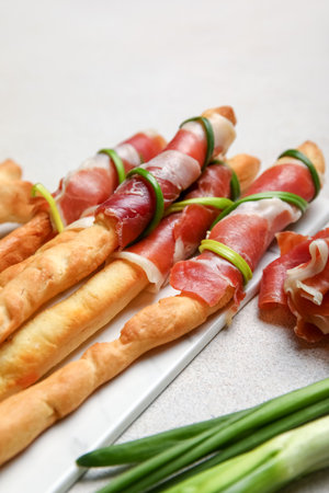 Board of tasty Italian Grissini with bacon on light background, closeupの写真素材