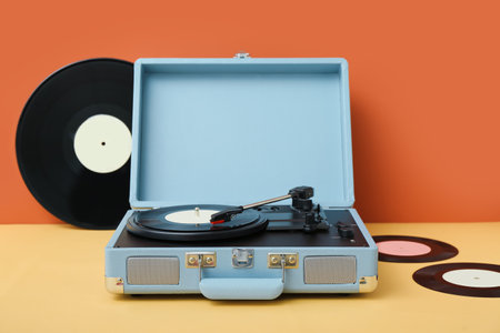 Record player with vinyl disks on table near orange wallの写真素材