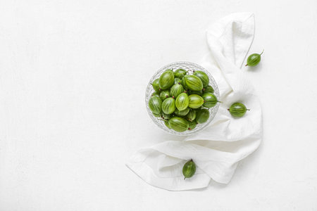 Glass bowl with fresh green gooseberry on white backgroundの写真素材
