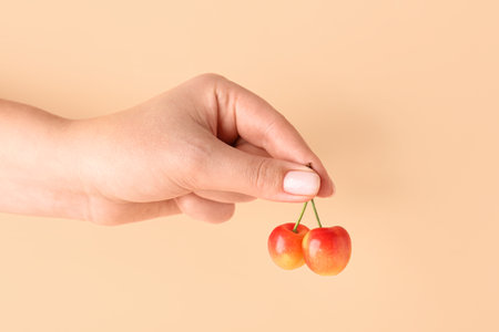 Woman holding sweet yellow cherry on orange backgroundの写真素材