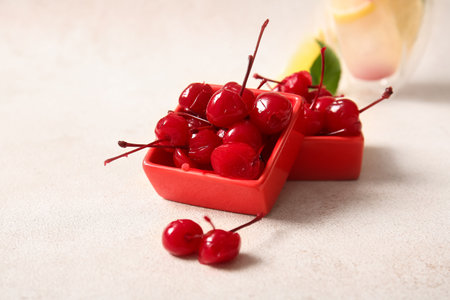 Bowls of tasty maraschino cherries on light backgroundの写真素材