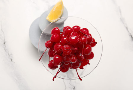 Glass of tasty maraschino cherries on white marble backgroundの写真素材